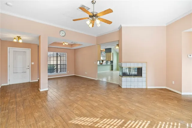 a view of an empty room with window and a kitchen
