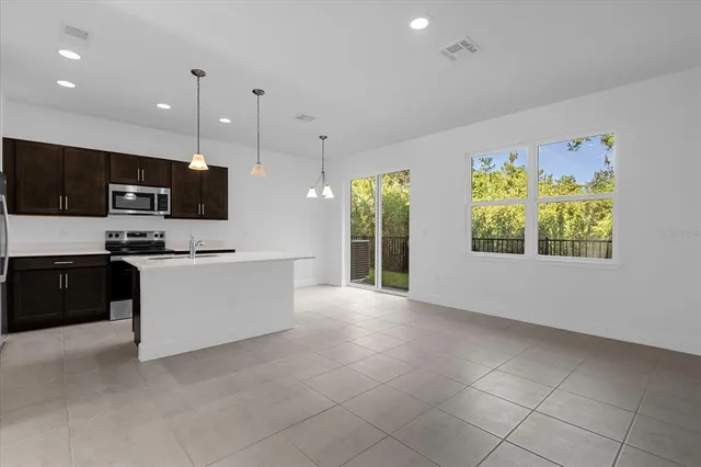 a large white kitchen with stainless steel appliances kitchen island granite countertop a stove a sink a microwave and a refrigerator