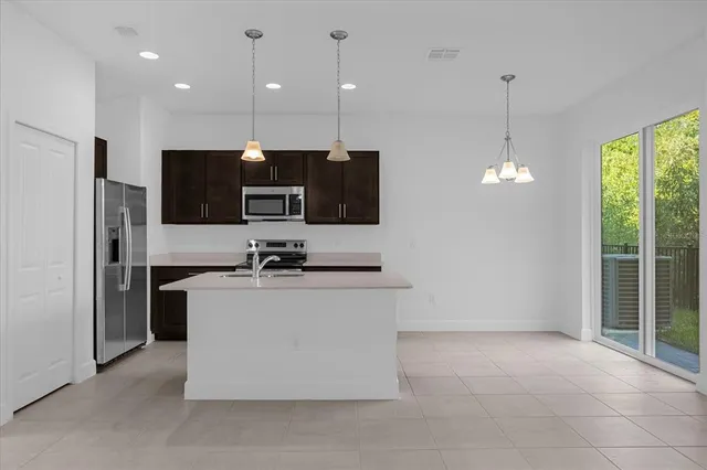 a kitchen with stainless steel appliances granite countertop a refrigerator a sink a stove a microwave and a refrigerator