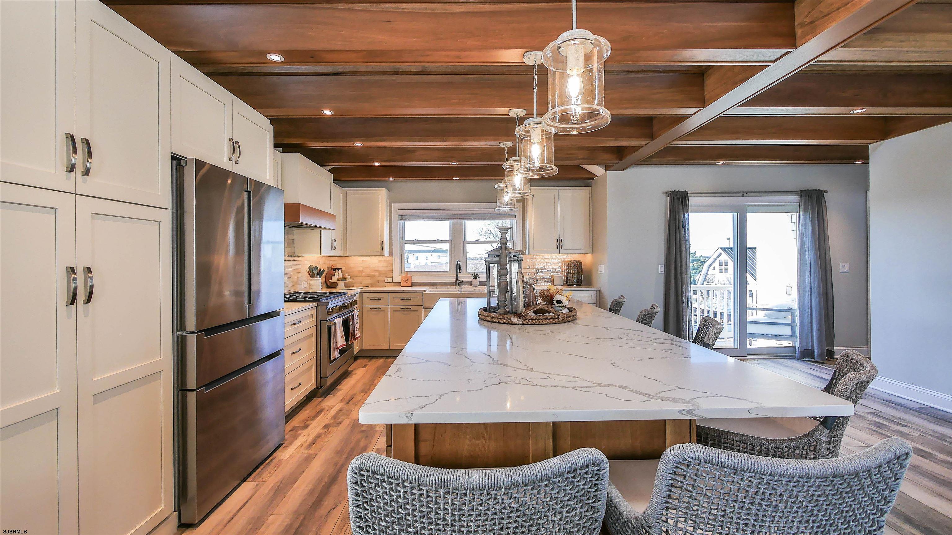 9 Commonwealth Avenue Strathmere, NJ 08248 - Photo 29 of 51 a kitchen with stainless steel appliances granite countertop a refrigerator a sink dishwasher a stove and a dining table with wooden floor