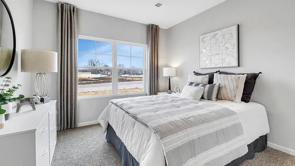 a bedroom with a bed and a lamp on dresser