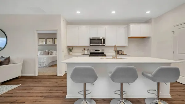 a kitchen with stainless steel appliances granite countertop a stove a sink a microwave a refrigerator and white cabinets with wooden floor