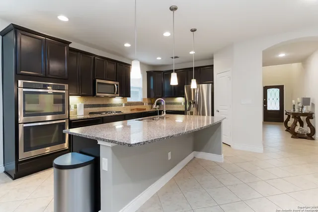 a large kitchen with kitchen island a counter space a sink and stainless steel appliances