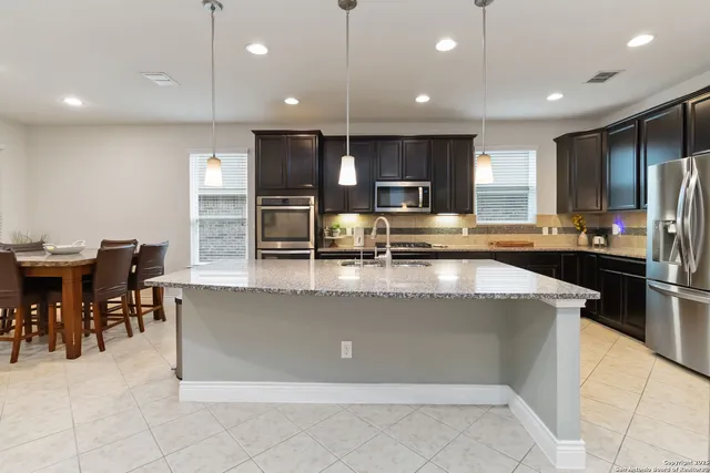 a large kitchen with kitchen island a large counter top stainless steel appliances and cabinets