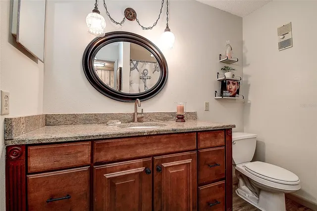 a bathroom with a granite countertop sink a mirror and shower