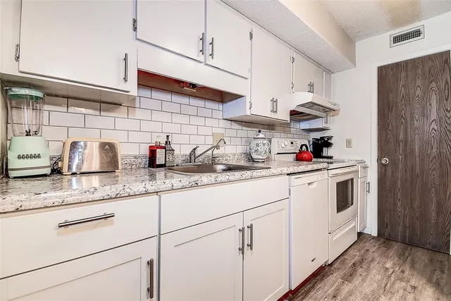 a kitchen with stainless steel appliances granite countertop a sink a stove and cabinets