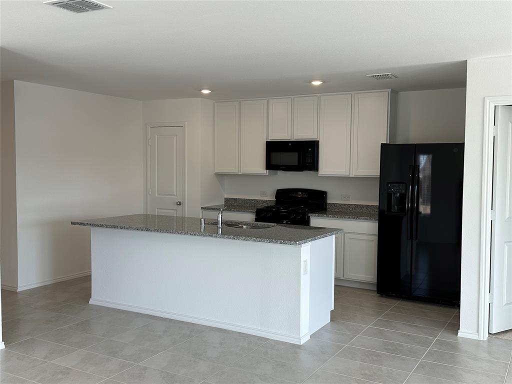 1729 High Perch Lane Forney, TX 75126 - Photo 3 of 16 Kitchen with black appliances, dark stone countertops, white cabinetry, a center island with sink, and recessed lighting
