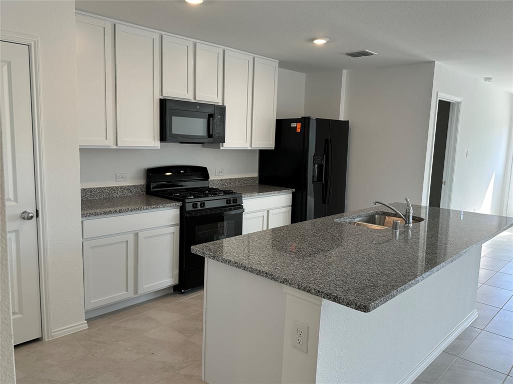 1729 High Perch Lane Forney, TX 75126 - Photo 4 of 16 Kitchen featuring black appliances, white cabinets, dark stone countertops, and an island with sink
