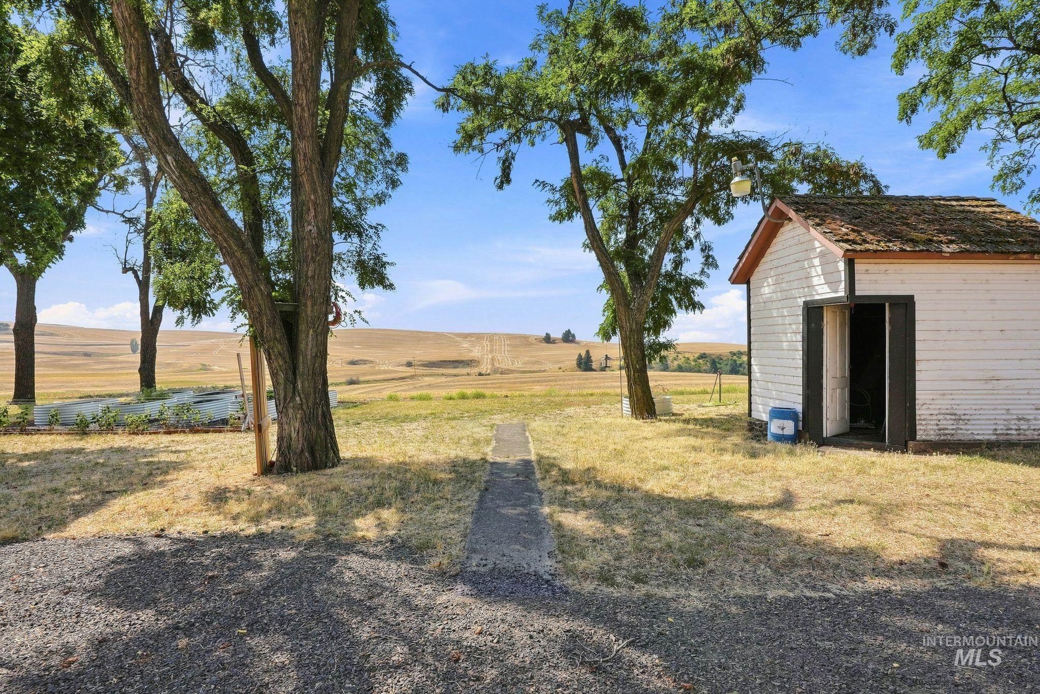 16078 Hoffman Road Kendrick, ID 83537 - Photo 32 of 47 White exterior building with a brown shingled roof, set on a gravel and grass ground