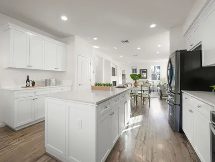 a kitchen with stainless steel appliances white cabinets sink and wooden floor