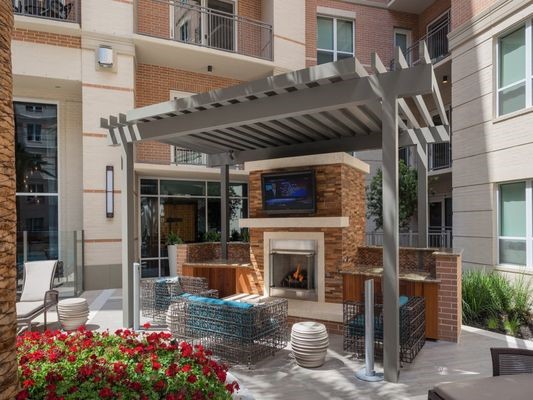 2724 Kipling Street, Unit 535 Houston, TX 77098 - Photo 20 of 30 Picture yourself ending a perfect day at this luxury fireside retreat. As the sun sets, you can gather with friends under the architectural pergola to watch the game on the outdoor big screen, all while the warmth of the stone fireplace creates an inviting, upscale ambiance. Sink into the plush, teal-accented loungers with a drink in hand, surrounded by vibrant landscaping and the tranquil energy of the nearby pool.