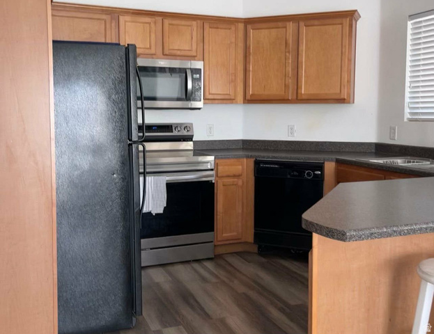 90 East Resaca Drive, Unit C11 Sandy, UT 84070 - Photo 5 of 27 Kitchen featuring black appliances, dark countertops, a peninsula, dark wood-style floors, and wood finish cabinetry