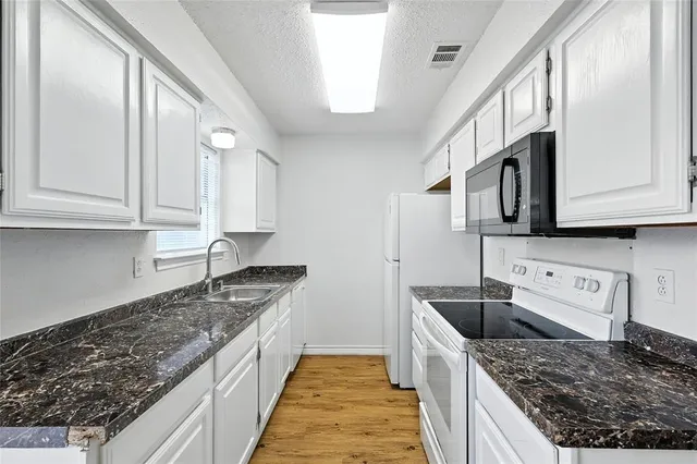 a kitchen with granite countertop a sink a stove and cabinets