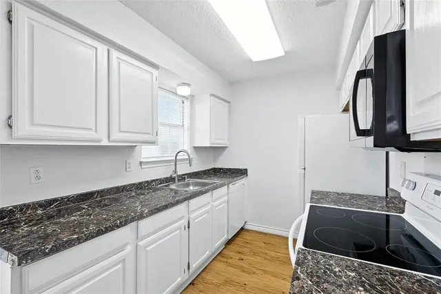 a kitchen with granite countertop a sink a stove and cabinets