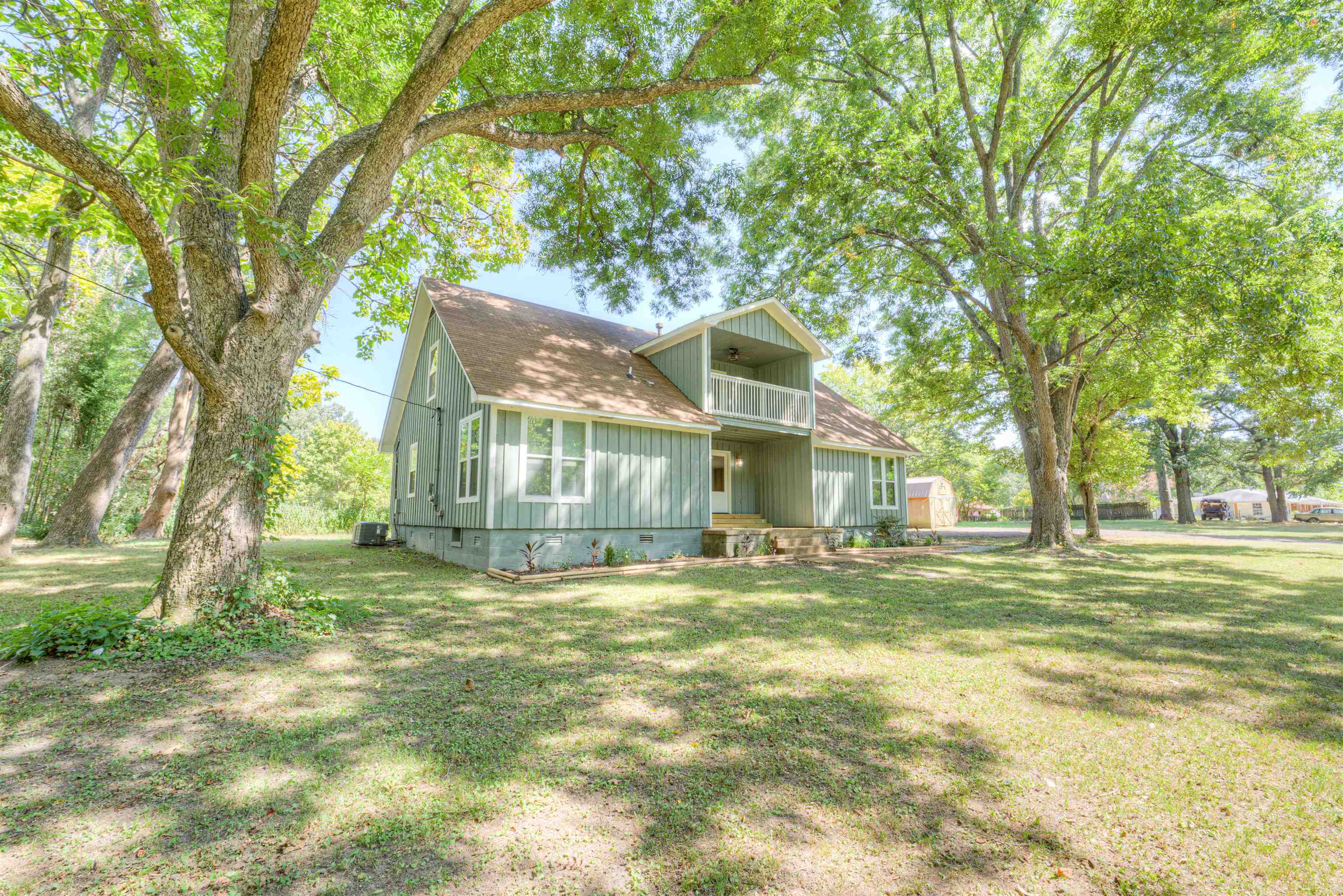 a view of a house with a big yard and large trees