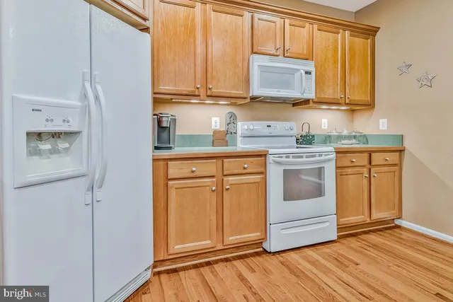 a kitchen with stainless steel appliances granite countertop a stove a sink dishwasher and a refrigerator with wooden cabinets