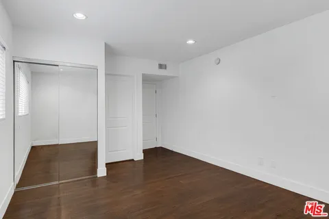 an empty room with wooden floor and closet