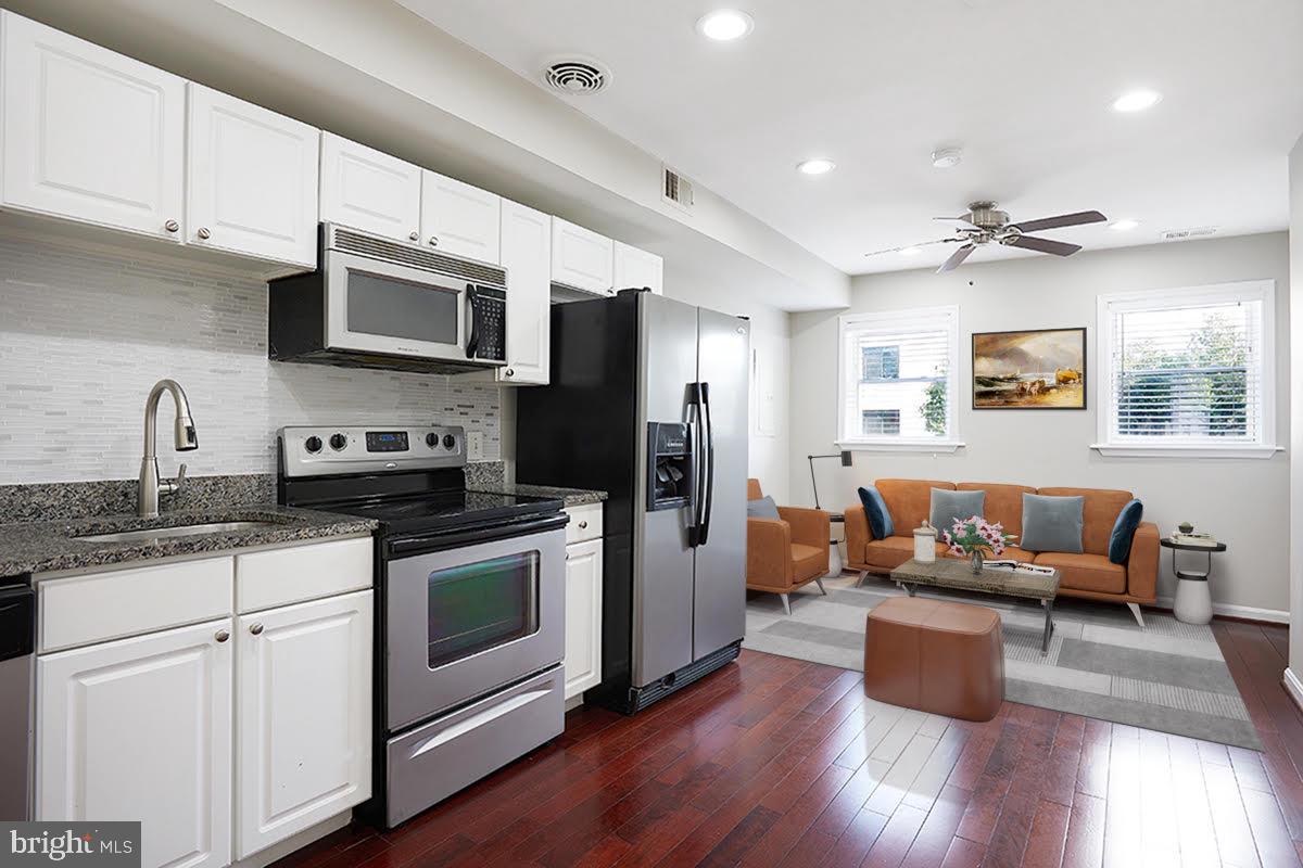 a kitchen with stainless steel appliances kitchen island granite countertop a stove a sink a refrigerator and white cabinets