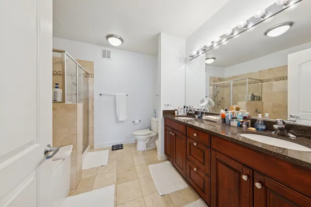 a spacious bathroom with a double vanity sink toilet mirror and bathtub