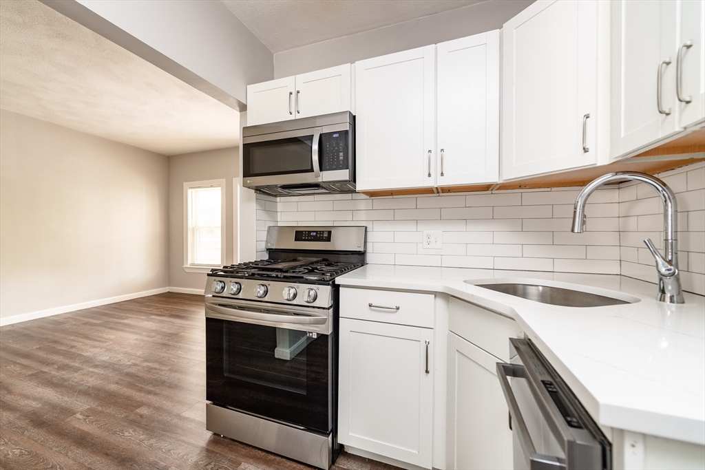 266-274 River Street Waltham, MA 02453 - Photo 11 of 27 a kitchen with white cabinets stainless steel appliances and sink