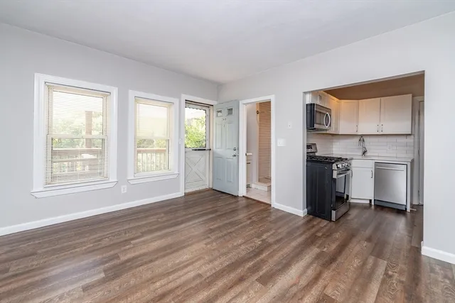 a view of kitchen and empty room with wooden floor kitchen view
