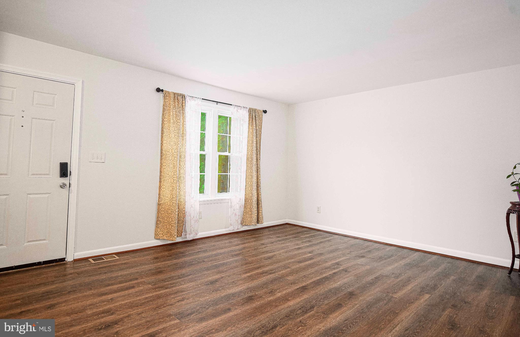 7105 Rutherford Green Circle Windsor Mill, MD 21244 - Photo 4 of 30 a view of an empty room with wooden floor and a window