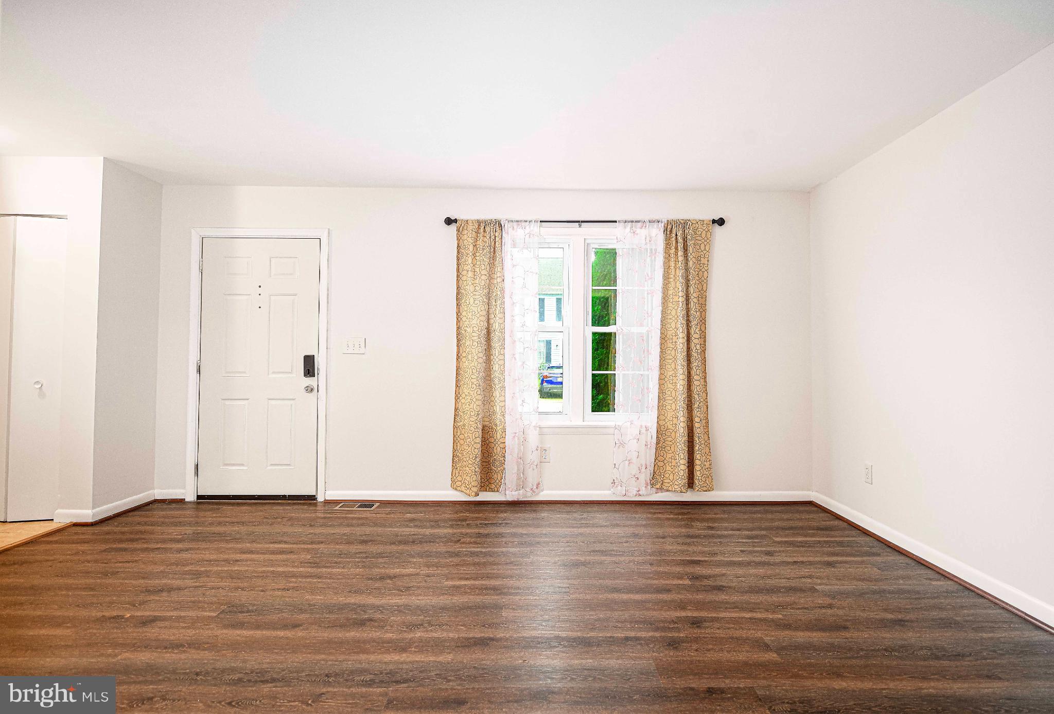 7105 Rutherford Green Circle Windsor Mill, MD 21244 - Photo 5 of 30 a view of an empty room with wooden floor and windows