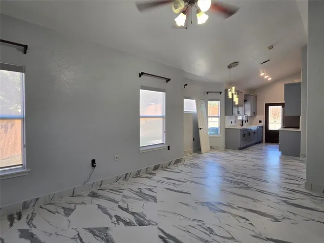 a view of an empty room and kitchen with wooden floor