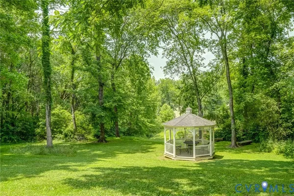 a white house with a big yard and large trees