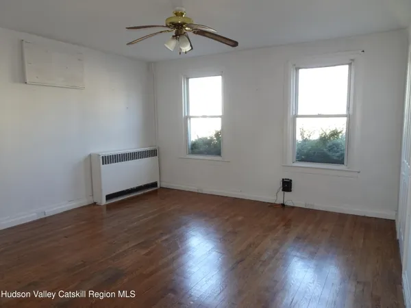 an empty room with wooden floor chandelier fan and windows