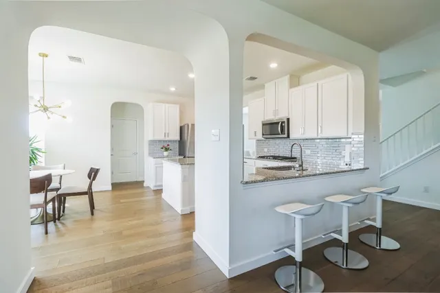 a kitchen with stainless steel appliances granite countertop a table and chairs in it