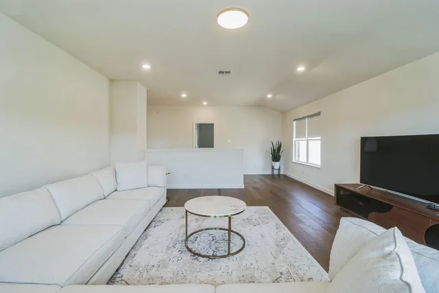 a living room with furniture a flat screen tv and a window