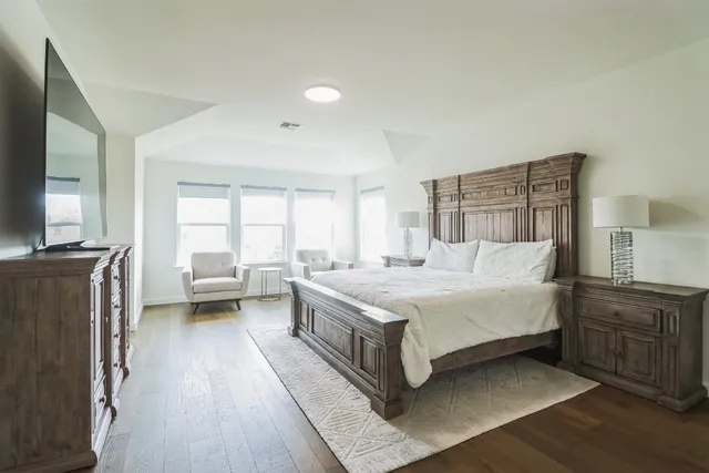 a spacious bedroom with a bed and a flat screen tv