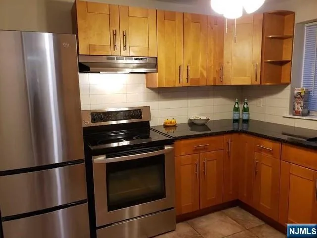 a kitchen with stainless steel appliances granite countertop a refrigerator stove and sink