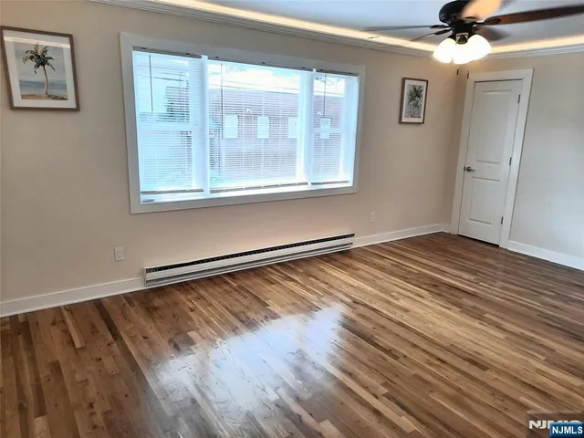 a view of an empty room with a window and wooden floor