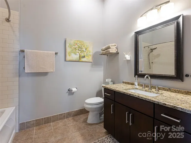 a bathroom with a granite countertop toilet sink and mirror