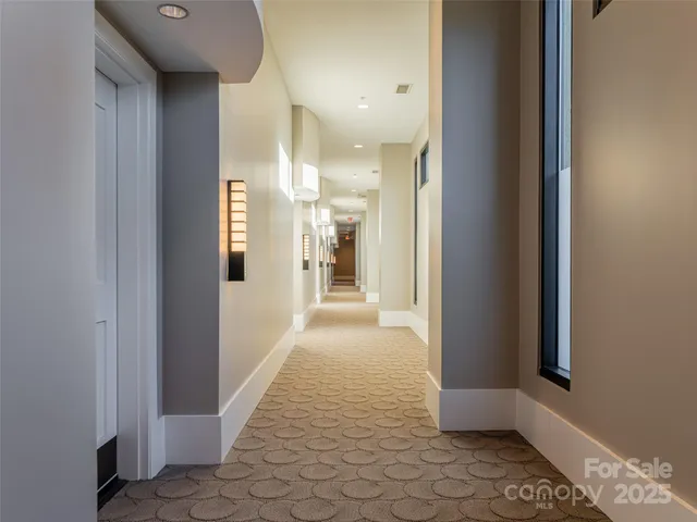 a view of a hallway with wooden floor and a bathroom