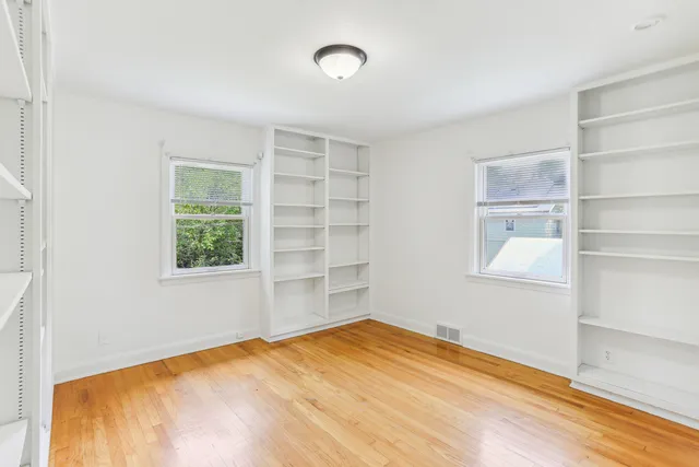 a view of empty room with wooden floor and fan