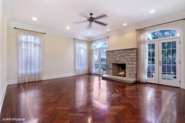 1055 Cherokee Road Wilmette, IL 60091 - Photo 5 of 25 an empty room with wooden floor a ceiling fan and a fireplace