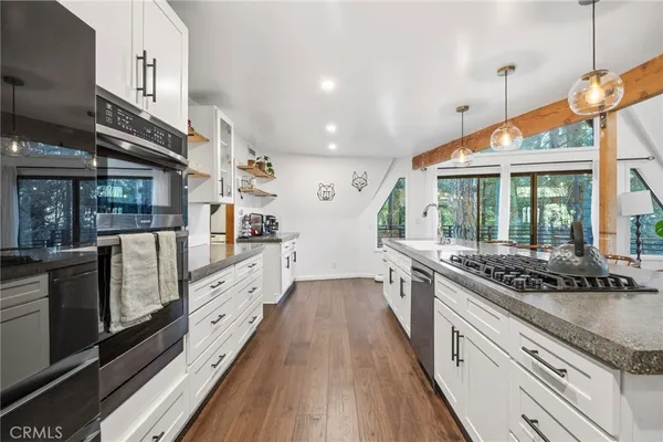 a kitchen with stainless steel appliances granite countertop a stove and a wooden floors