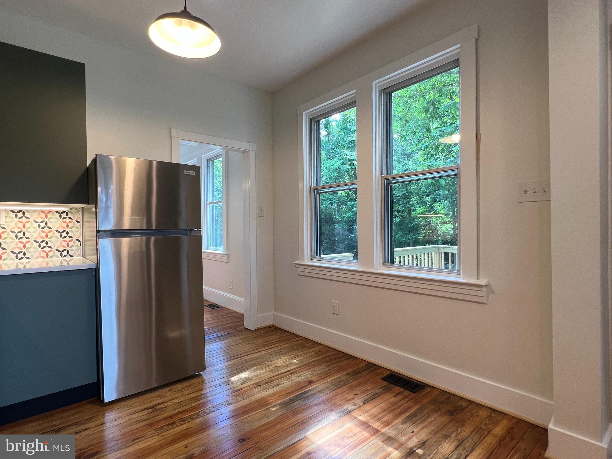 7308 Highbridge Road Bowie, MD 20720 - Photo 31 of 70 an empty room with wooden floor a kitchen view and windows