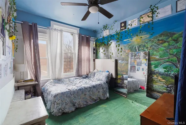a spacious bedroom with a bed painting on wall and a large window