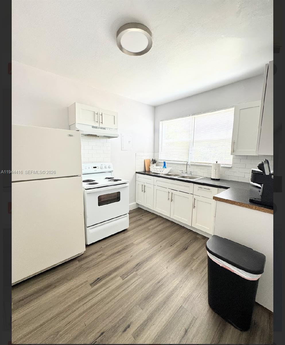 1821 Northwest 33rd Street Miami, FL 33142 - Photo 16 of 18 a kitchen with stainless steel appliances a stove a sink and white cabinets with wooden floors