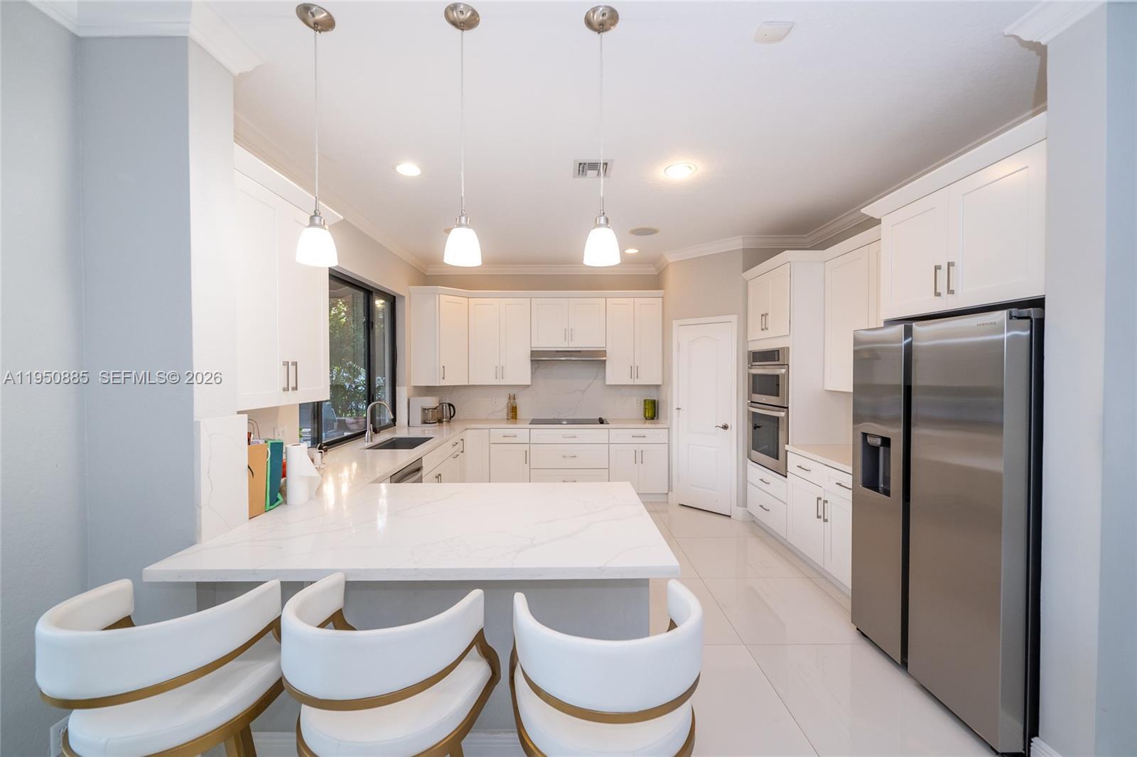 18540 Southwest 43rd Street Miramar, FL 33029 - Photo 9 of 56 a kitchen with a dining table chairs sink refrigerator and microwave