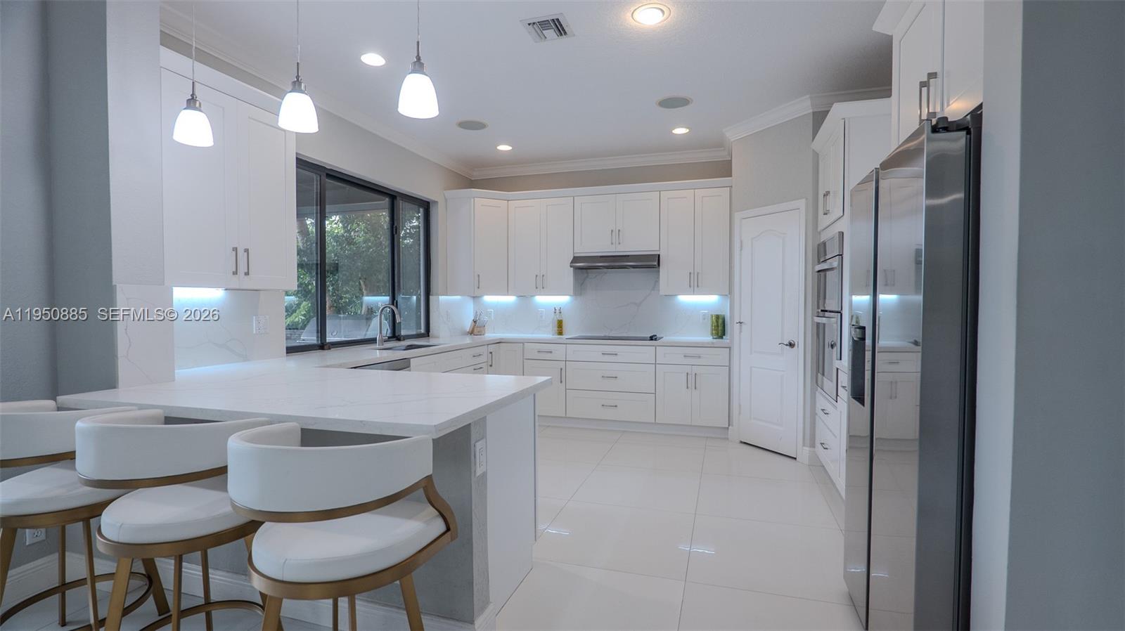 18540 Southwest 43rd Street Miramar, FL 33029 - Photo 10 of 56 a kitchen with white cabinets and chairs