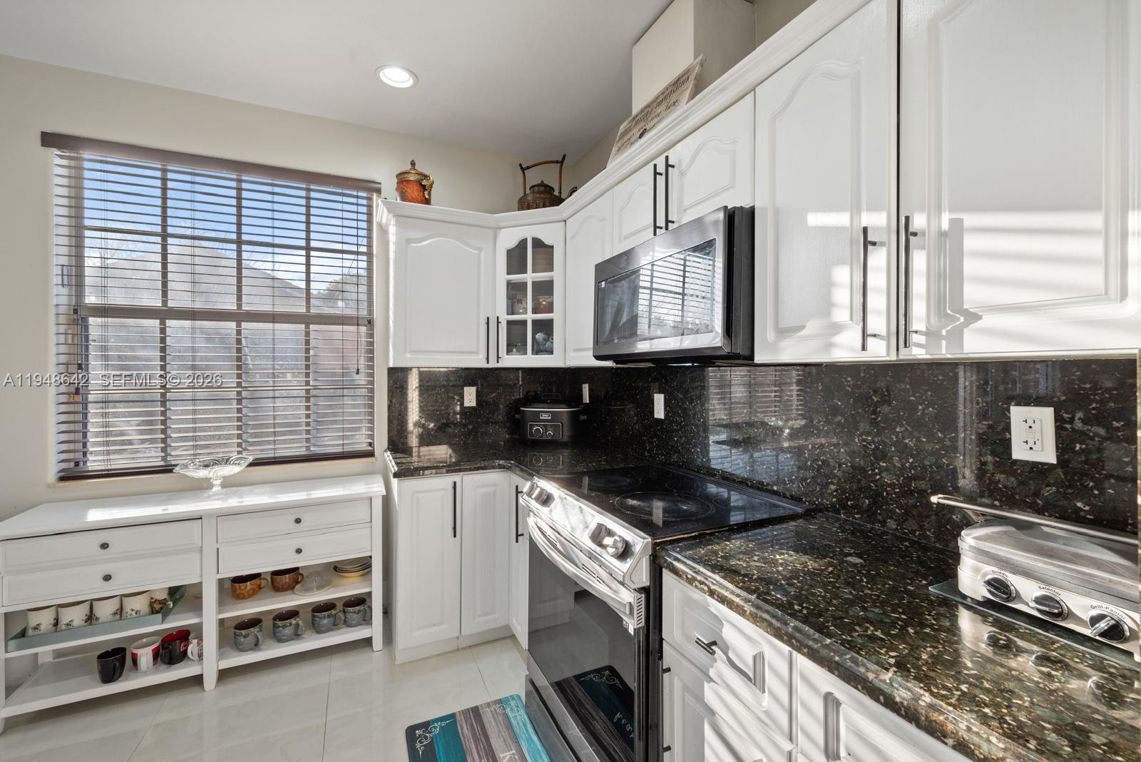 1360 Southwest 142nd Avenue Miami, FL 33184 - Photo 7 of 54 a kitchen with stainless steel appliances white cabinets and a stove top oven