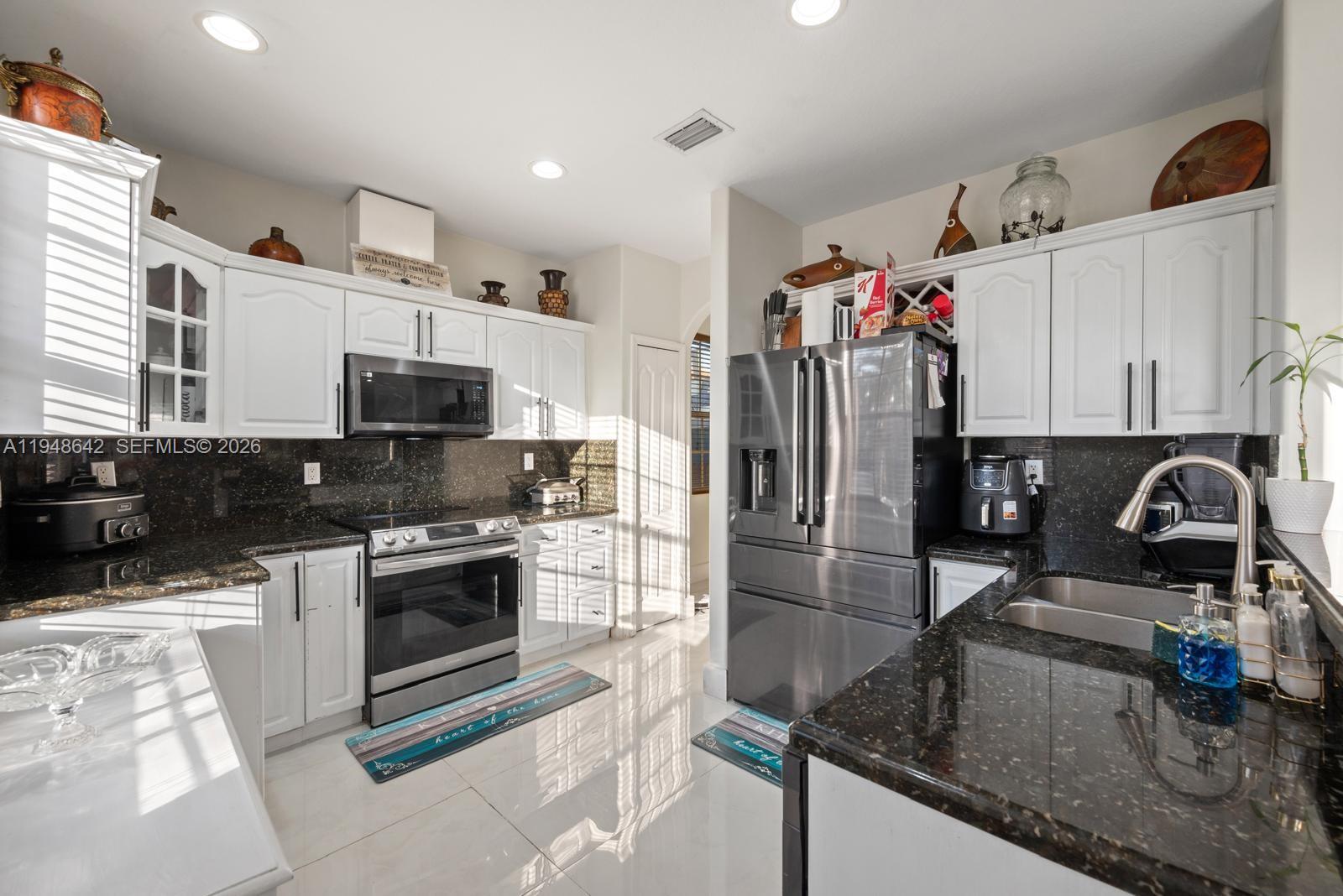 1360 Southwest 142nd Avenue Miami, FL 33184 - Photo 8 of 54 a kitchen with stainless steel appliances granite countertop a sink stove and refrigerator