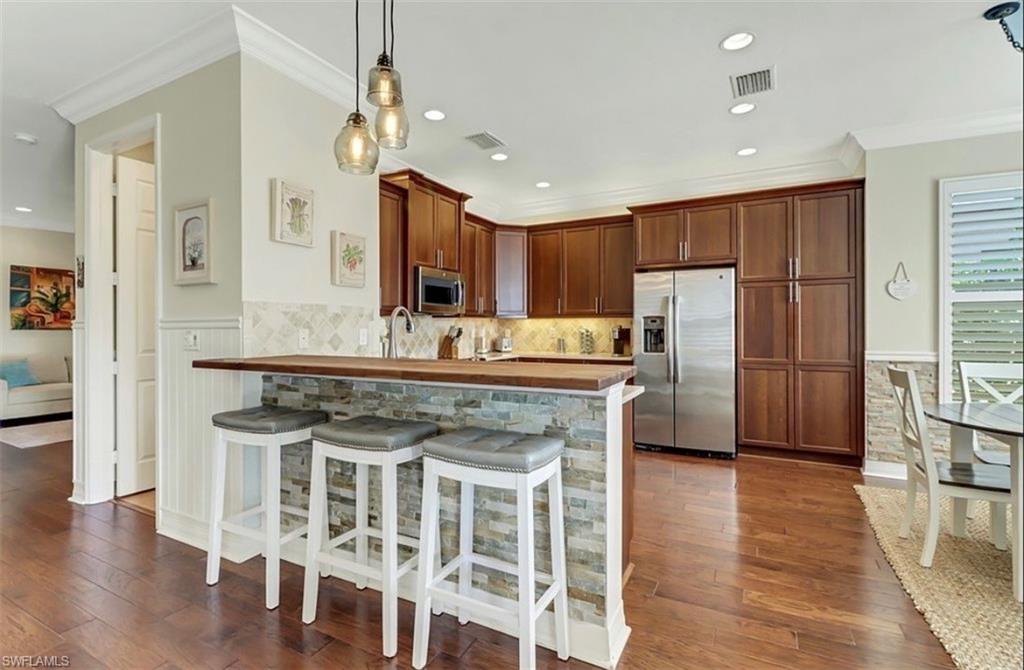 3402 Tigris Lane Naples, FL 34119 - Photo 11 of 50 a kitchen with stainless steel appliances granite countertop a refrigerator a stove a sink and white cabinets with wooden floor