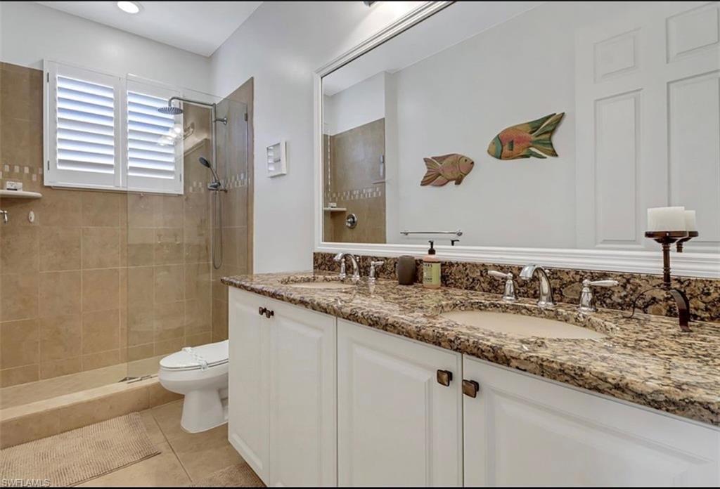 3402 Tigris Lane Naples, FL 34119 - Photo 31 of 50 a bathroom with a granite countertop sink a toilet and a mirror