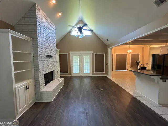 an empty room with wooden floor fan and windows